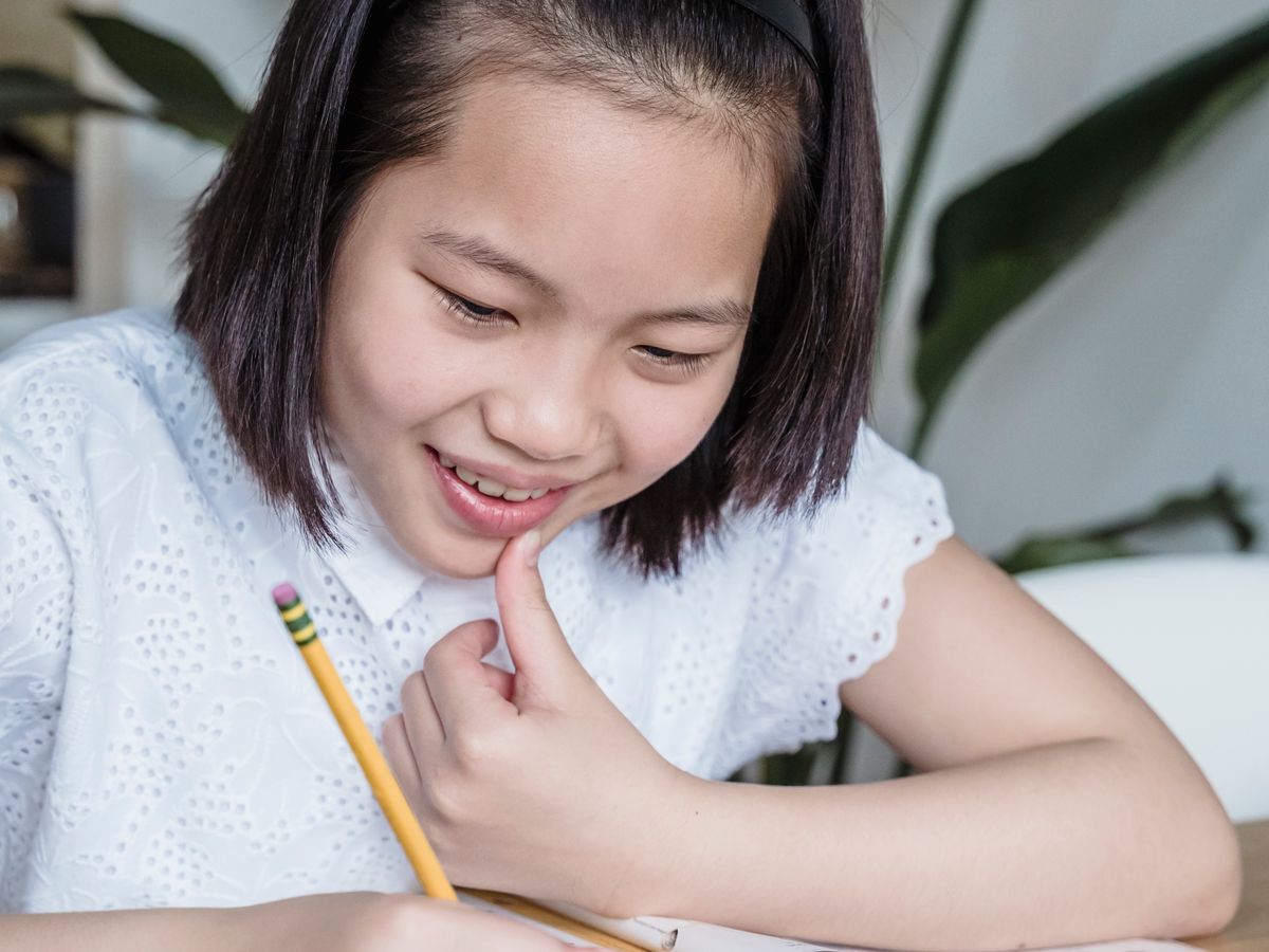 Smiling student writing with school supplies at home