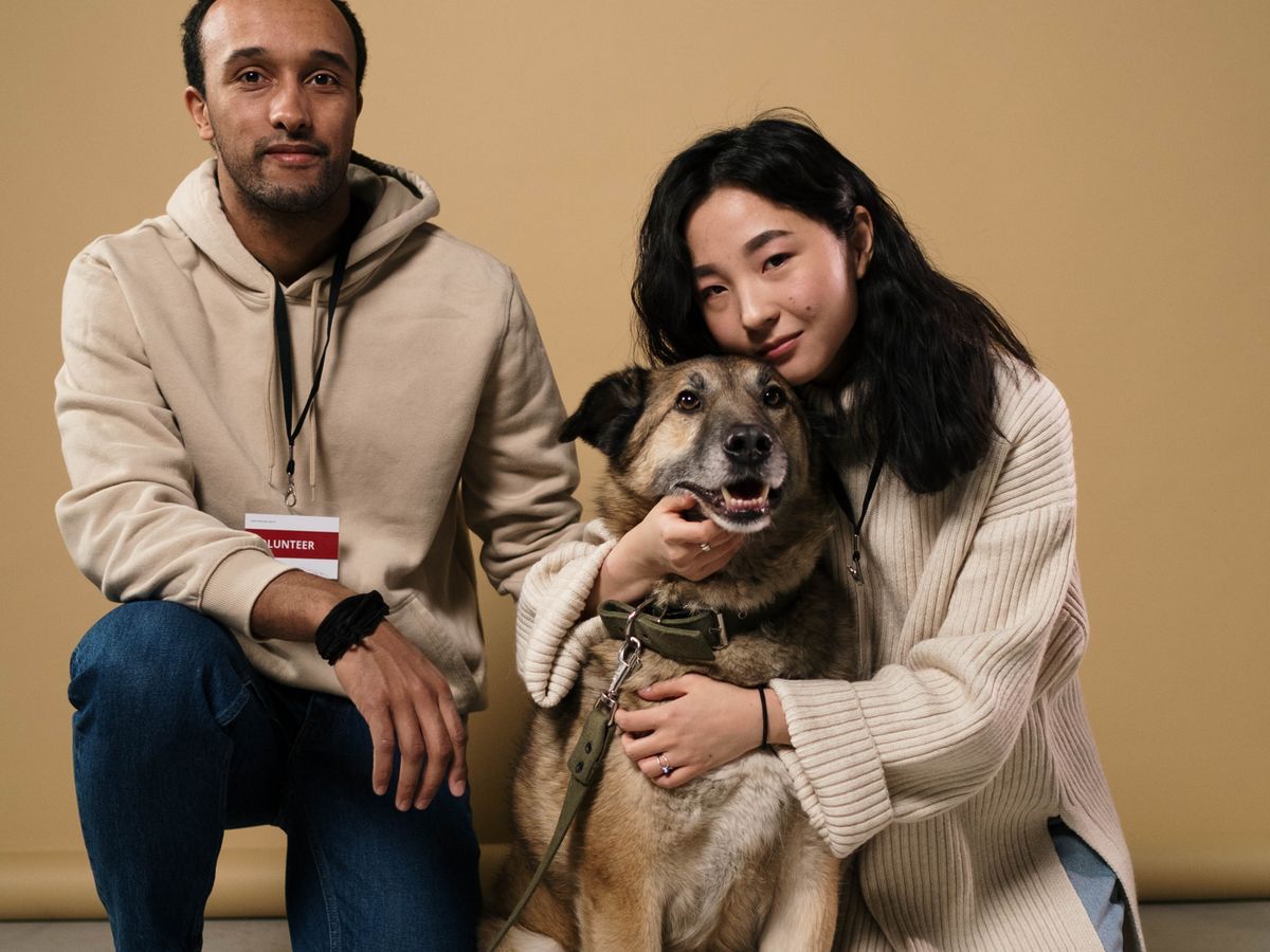 Two smiling pet owners with their dog