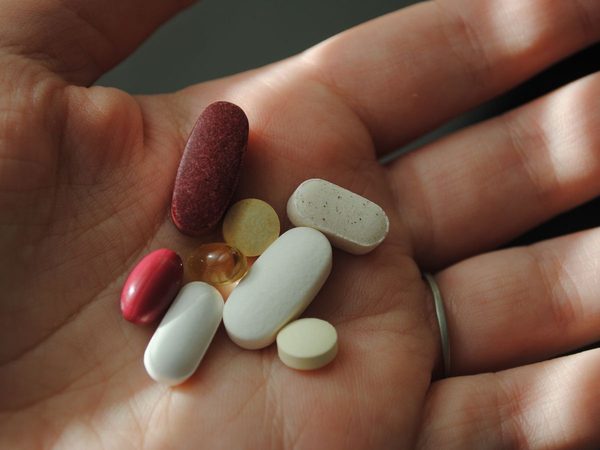Assorted vitamins and supplements held in a hand