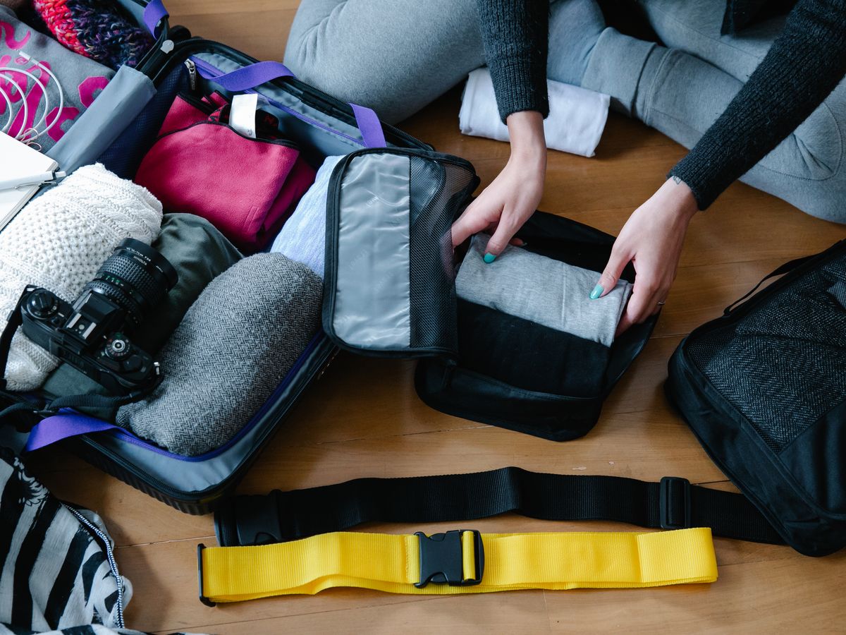 Person organizing clothes and accessories in a suitcase